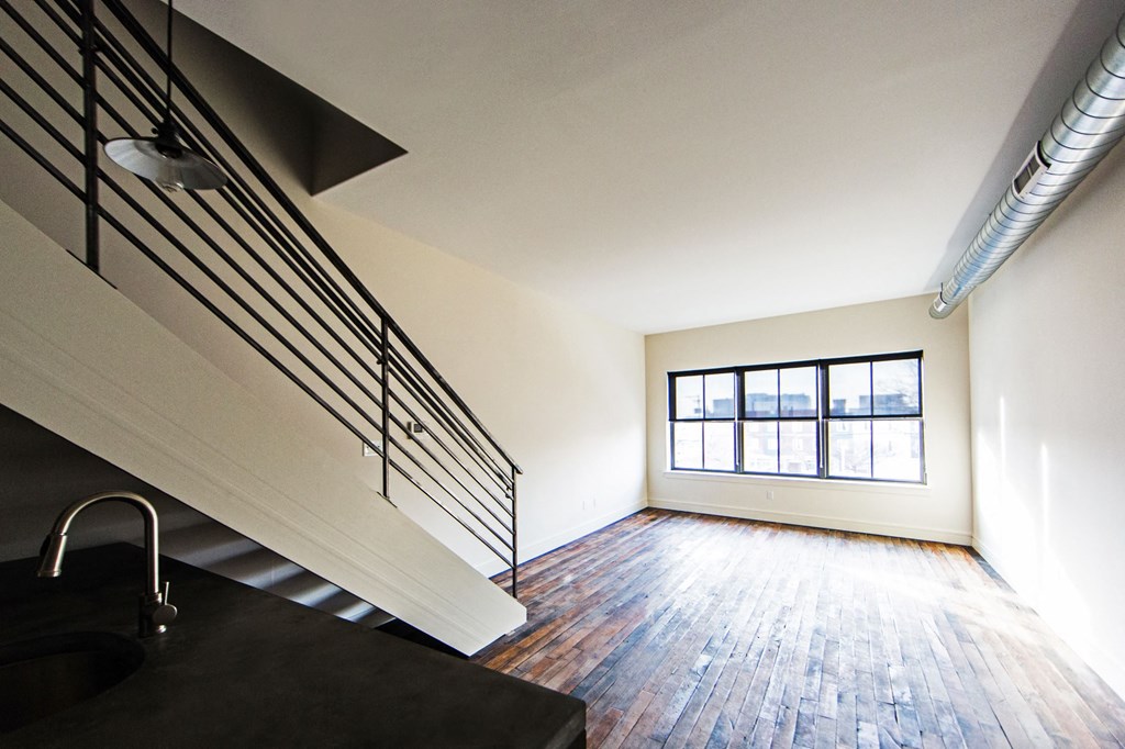 an empty living room with a staircase and a window