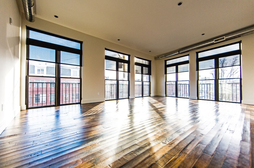 an empty living room with wood floors and large windows