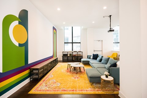 A living room with a yellow rug and a green couch.
