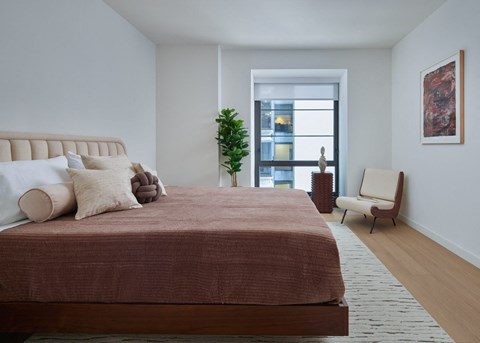 A bedroom with a large bed and a chair.