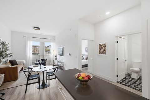 A modern living room with a black table and a bowl of fruit on it.