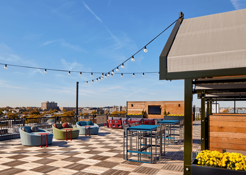 a rooftop patio with tables and chairs and a view of the city