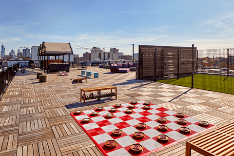 a rooftop party area with a chess board and a city skyline in the background