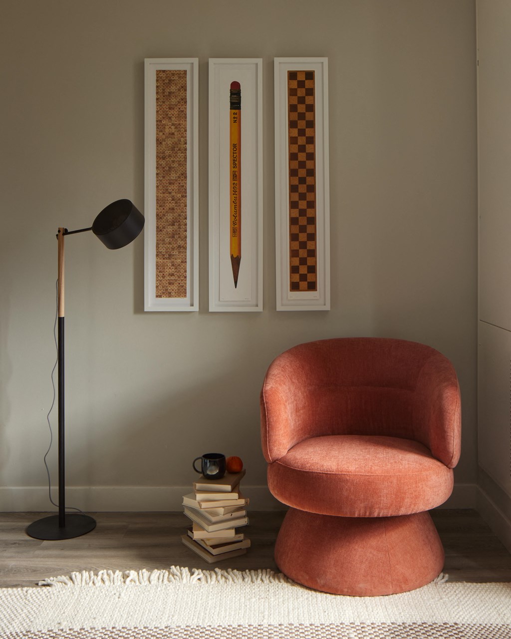 A snapshot of the living area in LVL West 1-Bedroom floorplan, featuring a cozy reading nook complete with an armchair, stack of books, reading lamp, and wall art.