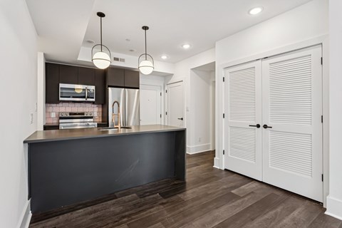 A kitchen with a black countertop and wooden flooring.