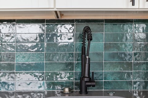 A black kitchen faucet with a pull-down sprayer is mounted on a sink.