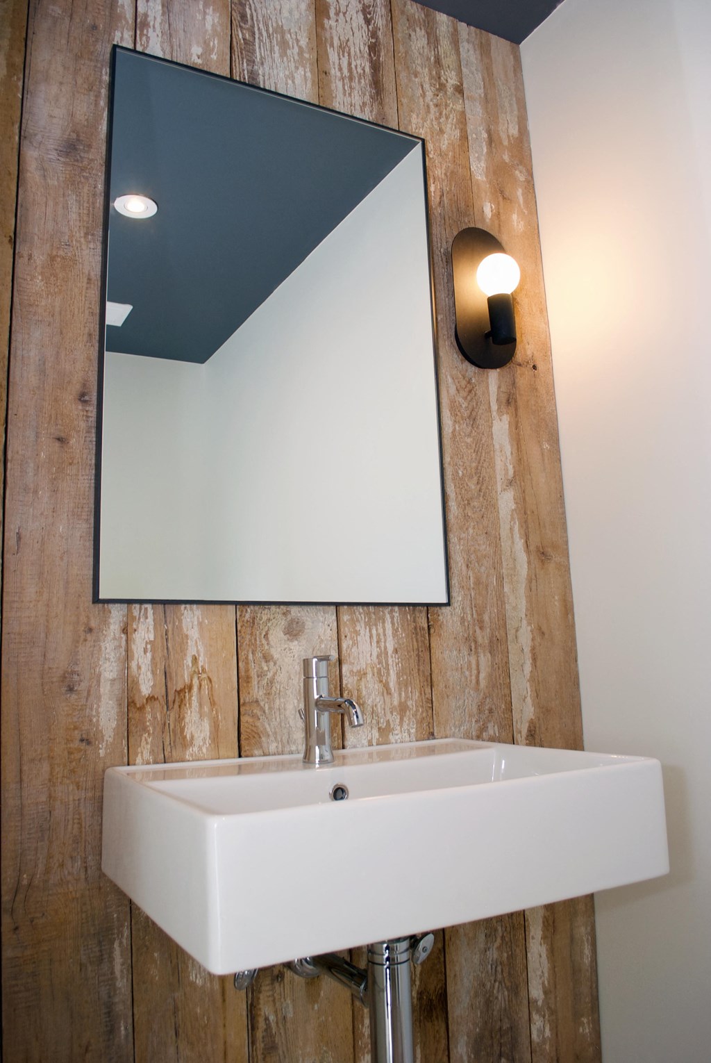 a bathroom sink with a mirror on a wooden wall