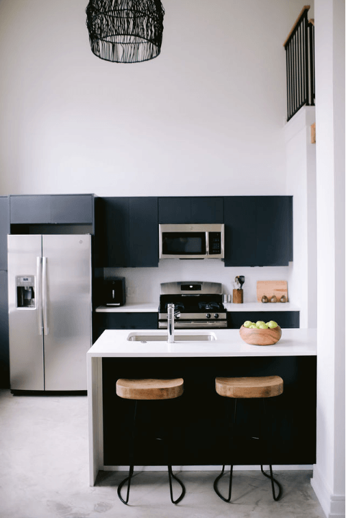 a kitchen with black cabinets and a white counter top and a refrigerator