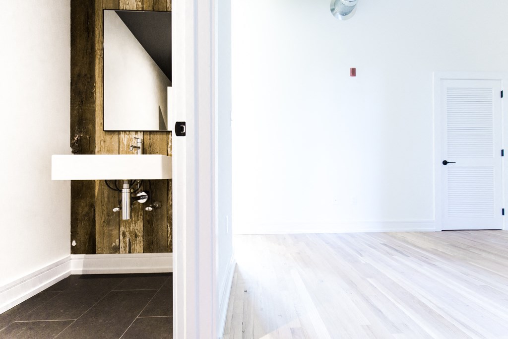 a bathroom with white walls and a wooden wall with a sink and a mirror