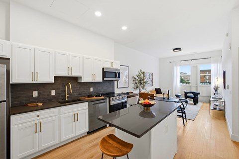 A modern kitchen with white cabinets and a black countertop.