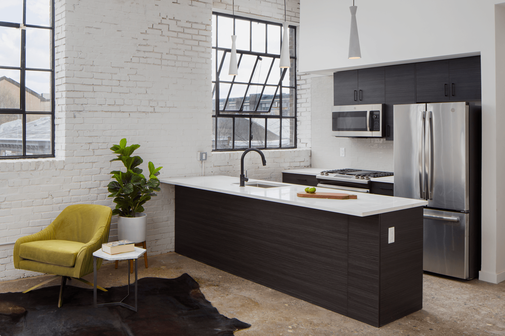 a kitchen with a white counter top and a stainless steel refrigerator