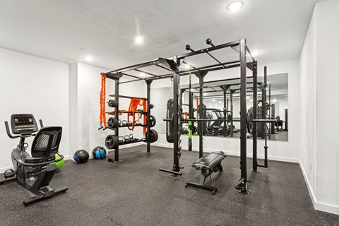 A gym with a variety of equipment including a weight bench, a leg press machine, and a squat rack.