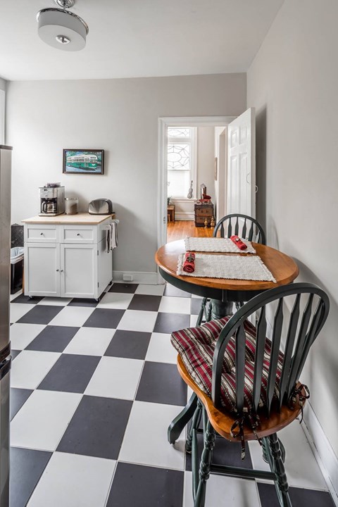 A black and white checkered floor in a kitchen with a table and chairs.