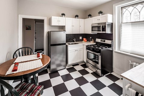 A black and white checkered floor in a kitchen with a refrigerator, oven, and sink.