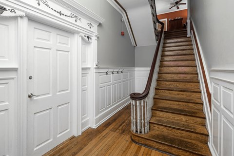 A staircase with a wooden handrail and white walls.