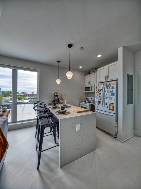 A kitchen with a refrigerator, microwave, and a dining table with chairs.