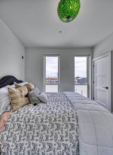 A bedroom with a large bed and a green lamp hanging from the ceiling.