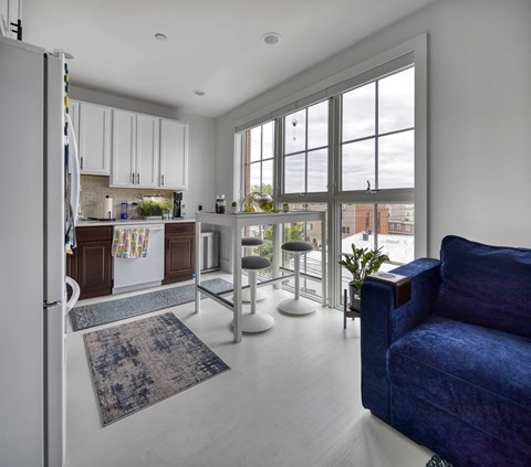 A blue couch is in the living room with a kitchen in the background.