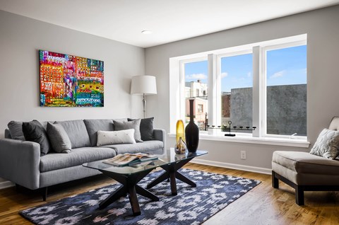 A living room with a grey couch, a black coffee table, and a large abstract painting on the wall.