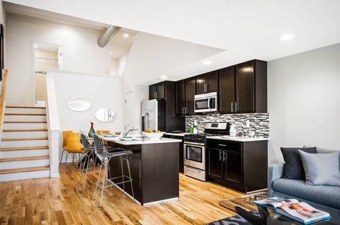 A modern kitchen with dark wood cabinets and a stone backsplash.