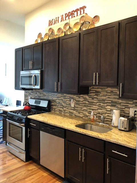 A kitchen with a stone backsplash and wooden cabinets.