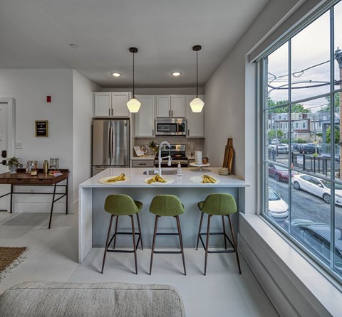 A modern kitchen with green bar stools and a white countertop.