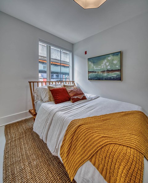 A bedroom with a bed covered in a white and yellow blanket.