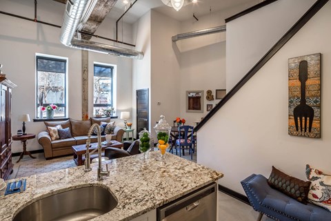 A kitchen with a marble countertop and a stainless steel sink.