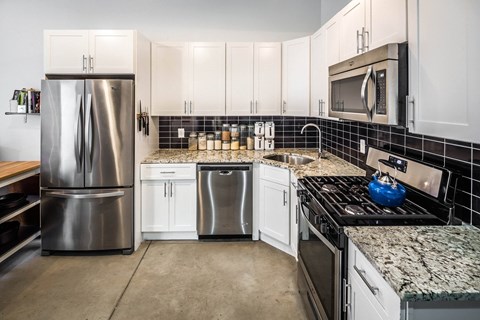 A kitchen with a stainless steel refrigerator, microwave, and oven.