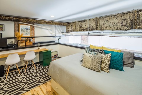A bedroom with a bed, desk, and chair.