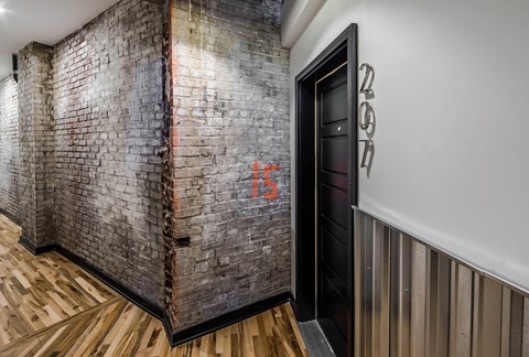 A hallway with a brick wall and a wooden floor.