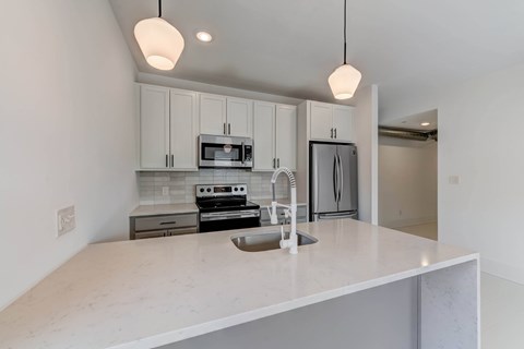 A kitchen with a white countertop and a microwave above it.