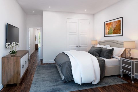 A modern bedroom with a large bed and a TV on the wall.