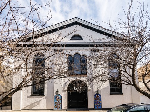 A white building with a black roof and a black door with a blue and red design on it.
