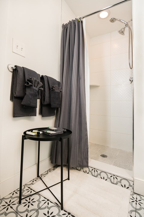 A bathroom with a black table and a grey shower curtain.