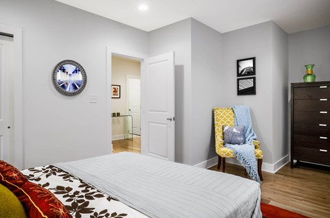 A bedroom with a bed, a chair, and a dresser.