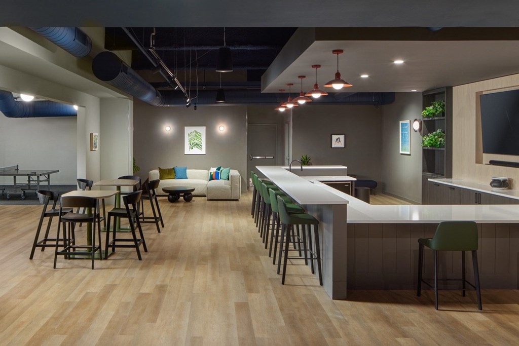 A modern bar with wooden floors and a long counter.