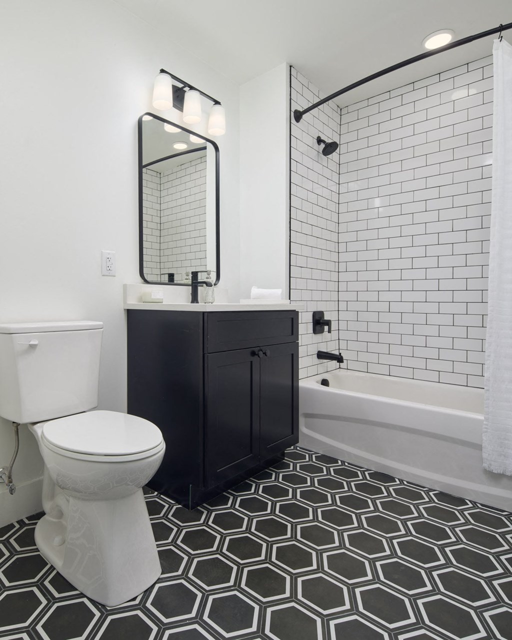 a black and white bathroom with a toilet and a shower