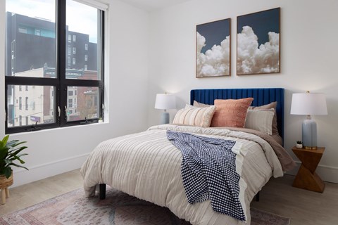 A bedroom with a large bed and two paintings on the wall.
