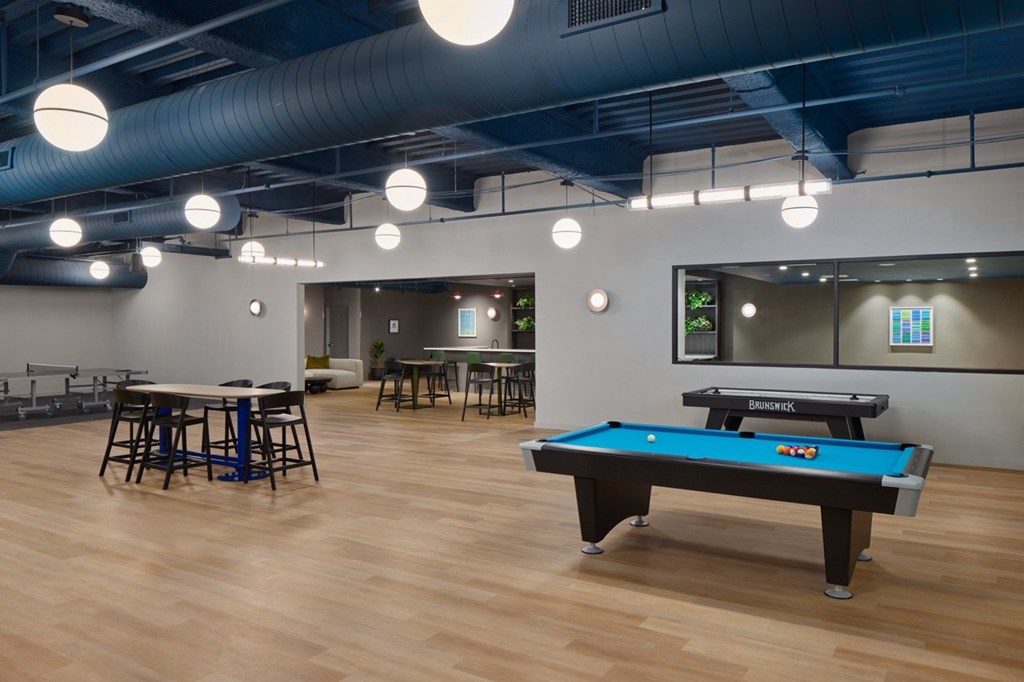 A pool table is in the middle of a room with a bar and a ping pong table.