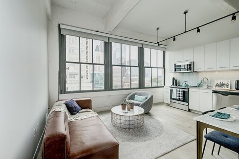 A modern living room with a brown leather couch and a large window.