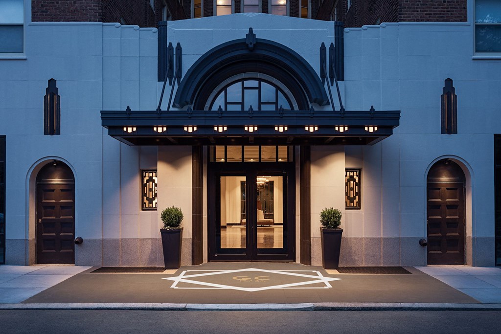 A building entrance with a large arched window and two potted plants on either side.