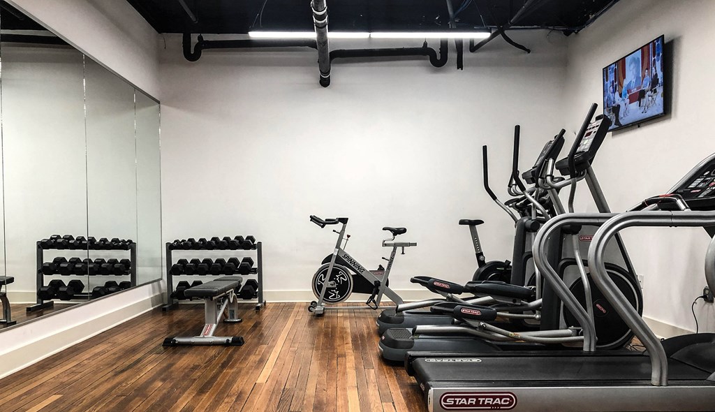 a gym with cardio equipment and a tv on the wall
