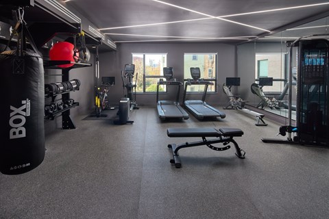 A gym with a punching bag and a bench.