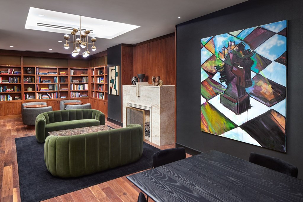A living room with a fireplace, bookshelves, and a large painting on the wall.