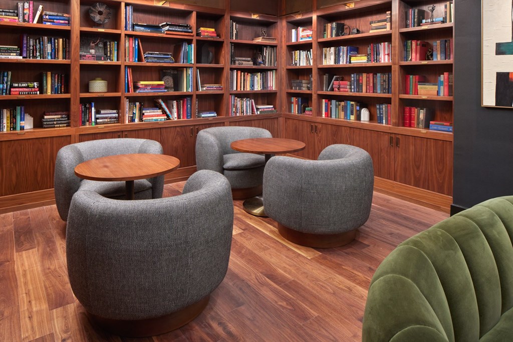 A room with a bookshelf filled with books and a few grey chairs.