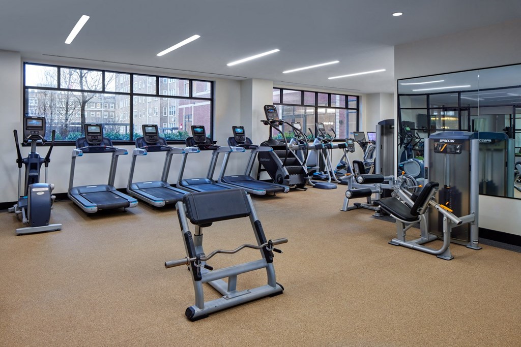 A gym with a variety of equipment including treadmills, stationary bikes, and weight machines.