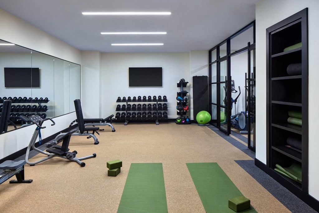 A gym with exercise equipment and a green mat on the floor.