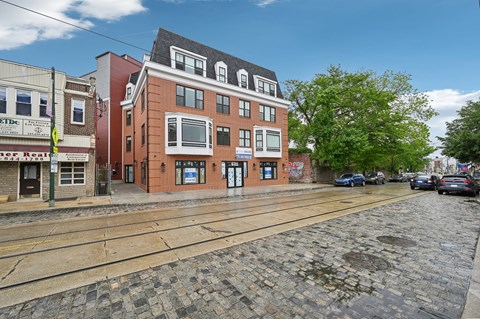 A cobblestone street with a building on the right and a car parked on the street.