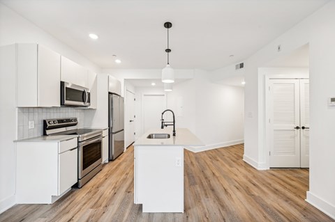 A modern kitchen with white cabinets and a wooden floor.